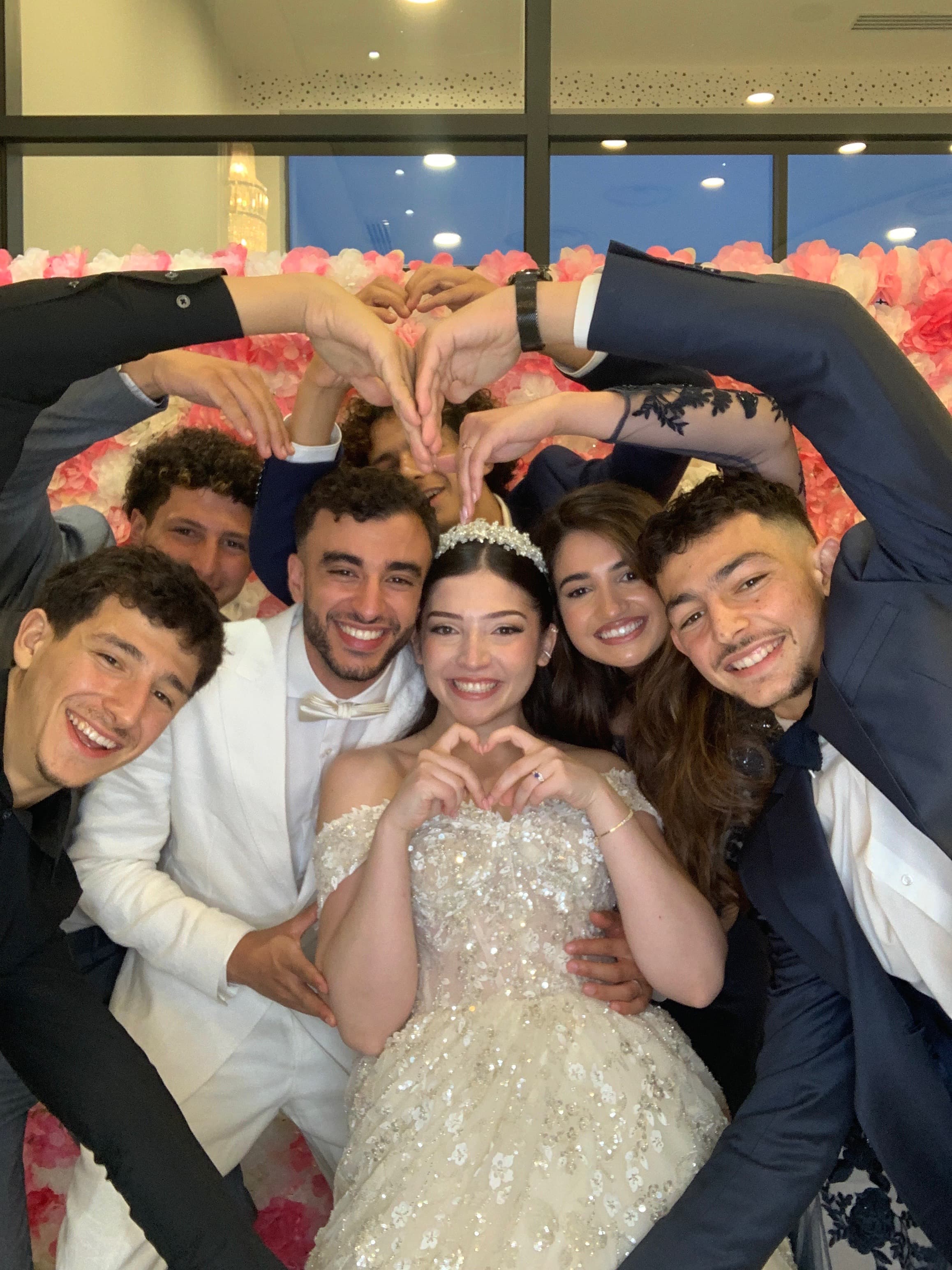 Couple de mariés entouré de leurs proches formant un coeur